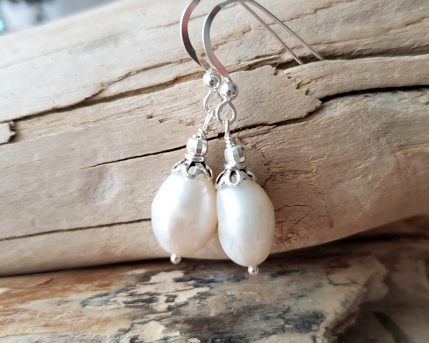 Large White Baroque Pearl Dangle Earrings with decorative silver beads and French earring hooks on wood background 