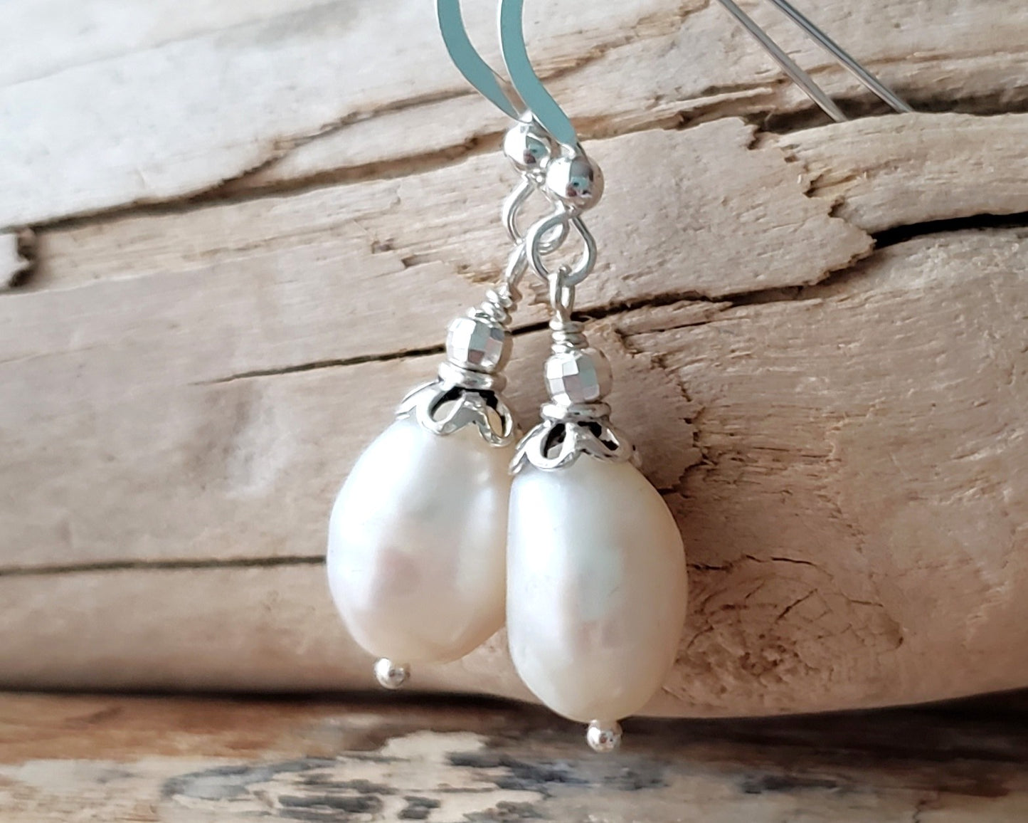 Large White Baroque Pearl Dangle Earrings with decorative silver beads and French earring hooks on wood background 