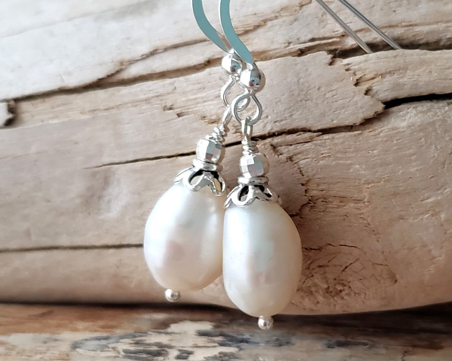Large White Baroque Pearl Dangle Earrings with decorative silver beads and French earring hooks on wood background 
