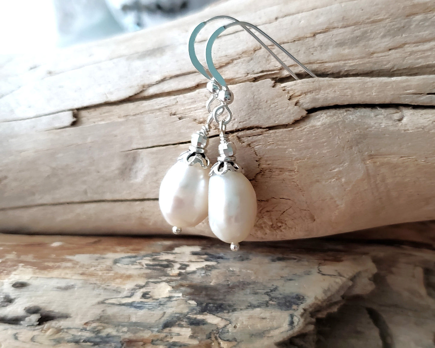 Large White Baroque Pearl Dangle Earrings with decorative silver beads and French earring hooks on wood background 