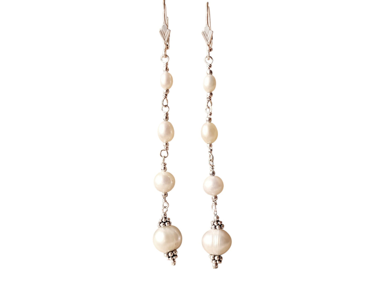 Long art deco style pearl earrings, white Freshwater Cultured Pearls, accented with fancy Sterling Silver beads on lever back earrings hooks on white background
