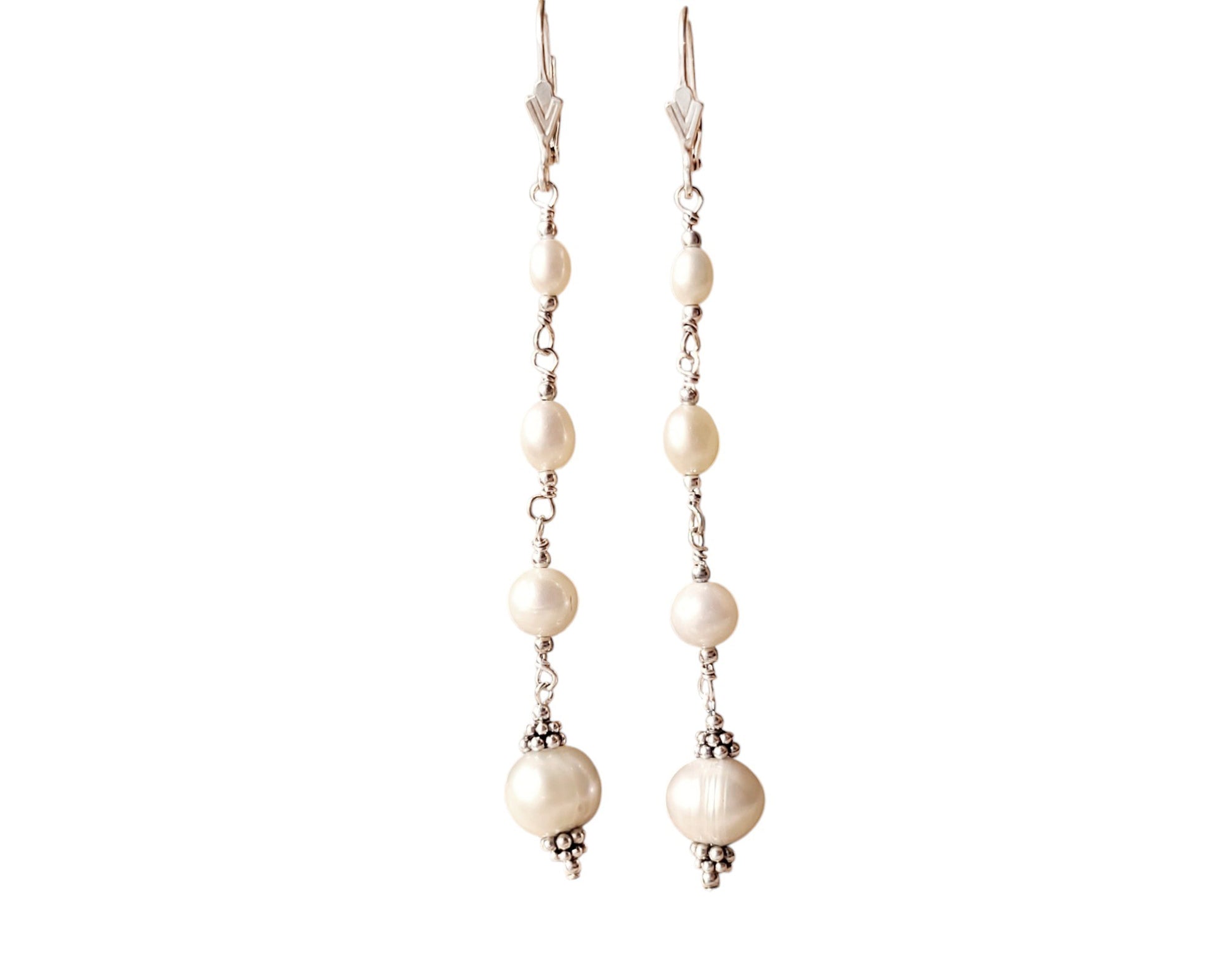 Long art deco style pearl earrings, white Freshwater Cultured Pearls, accented with fancy Sterling Silver beads on lever back earrings hooks on white background
