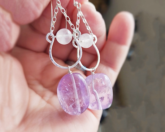Long Handmade Amethyst Nugget Rose Quartz Dangle Chandelier Earrings with translucent lavender Amethyst and pale pink Rose Quartz and french earrings hooks displayed in a hand 