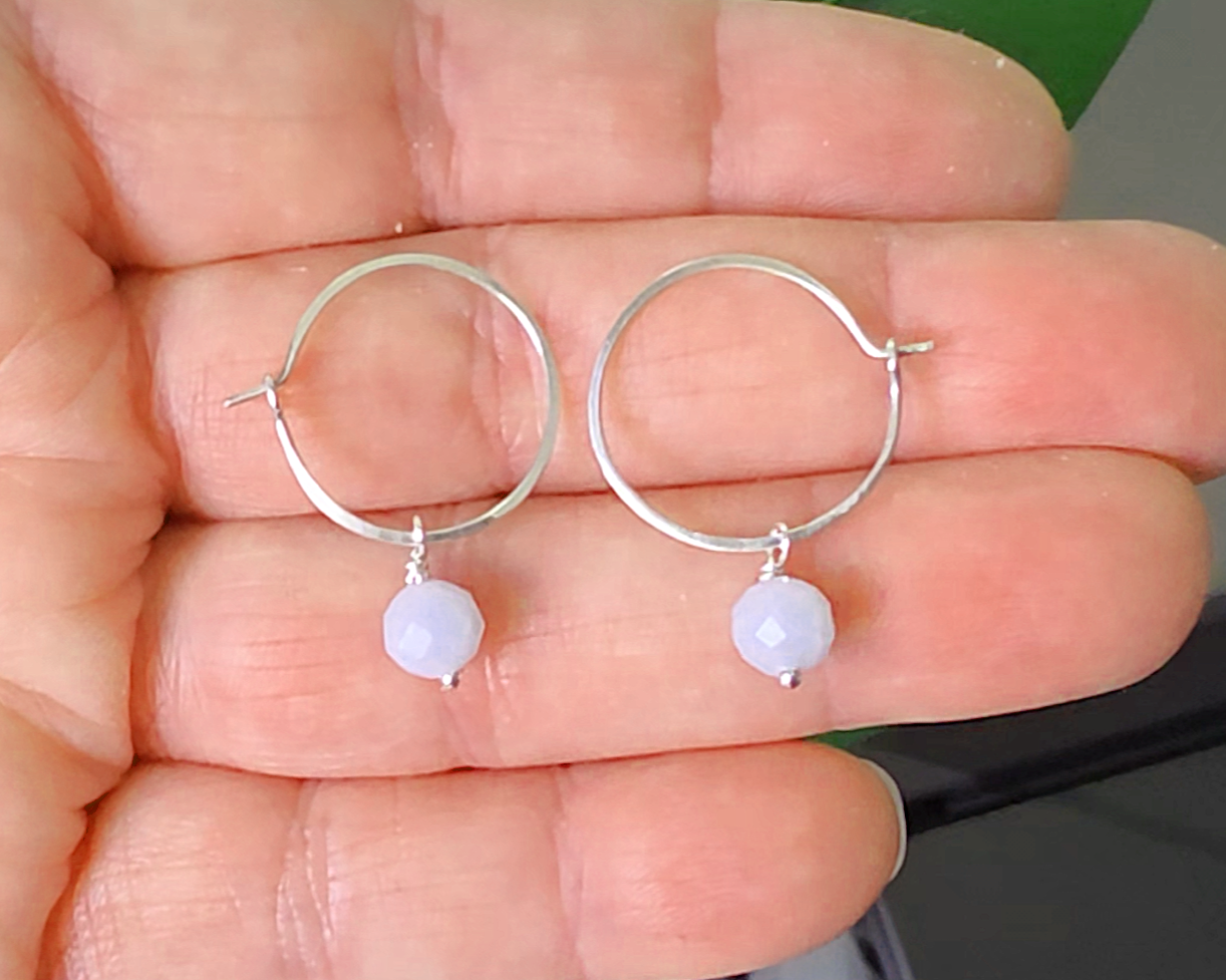 Sterling Silver hoop earrings with pale blue aquamarine dangles, on a hand