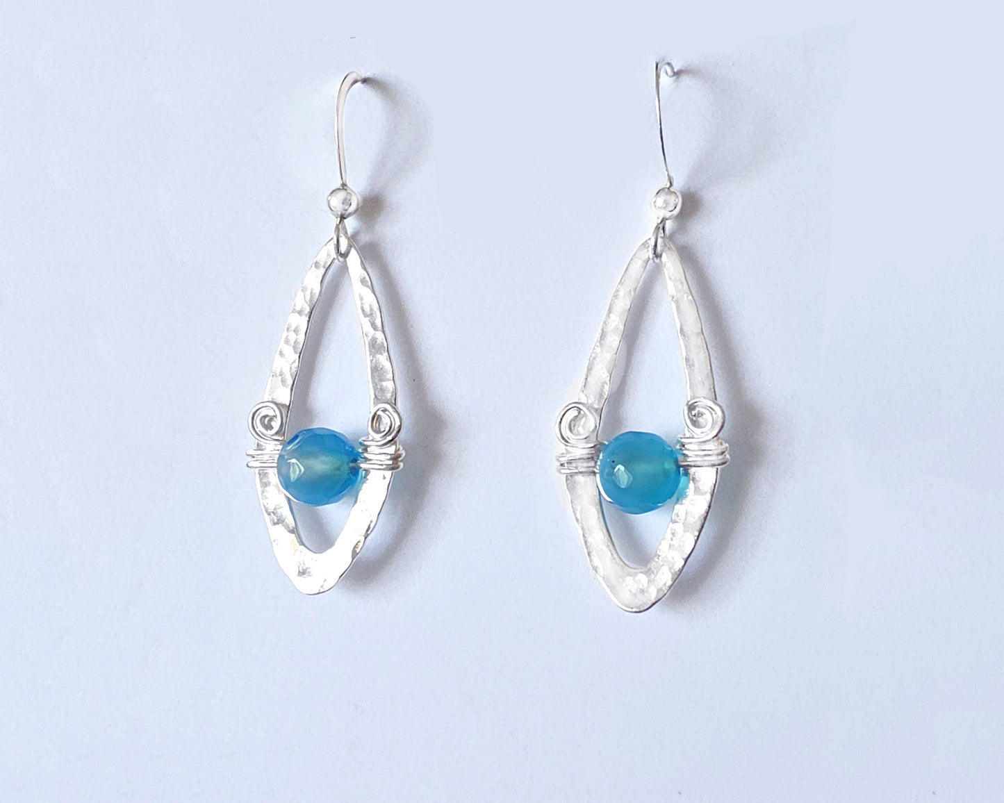 Long Sterling Silver Earrings with Blue Banded Agate stones and Celtic Eternity Coil designs on a wing like hammered design on French style earring hooks, on white background 