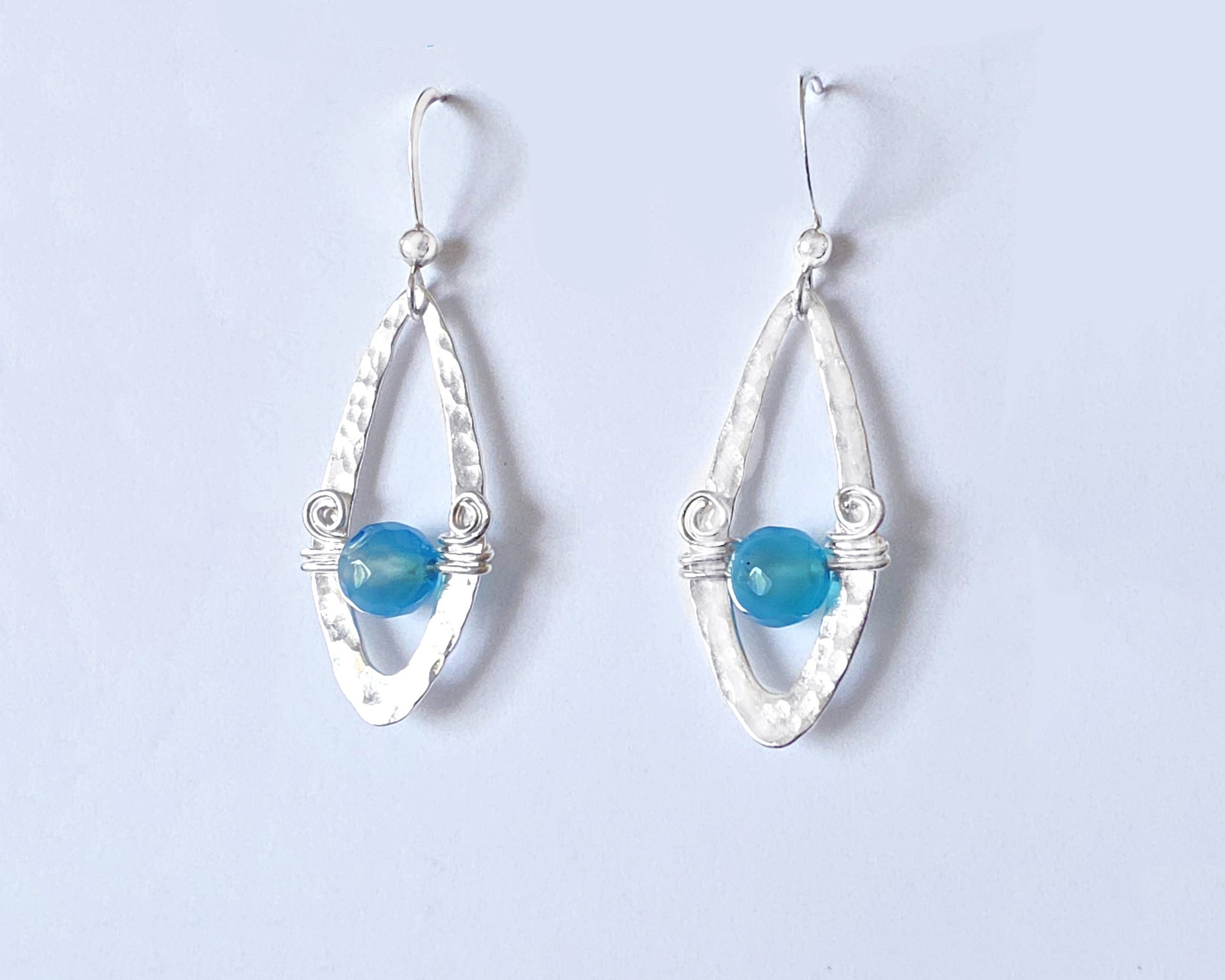 Long Sterling Silver Earrings with Blue Banded Agate stones and Celtic Eternity Coil designs on a wing like hammered design on French style earring hooks, on white background 