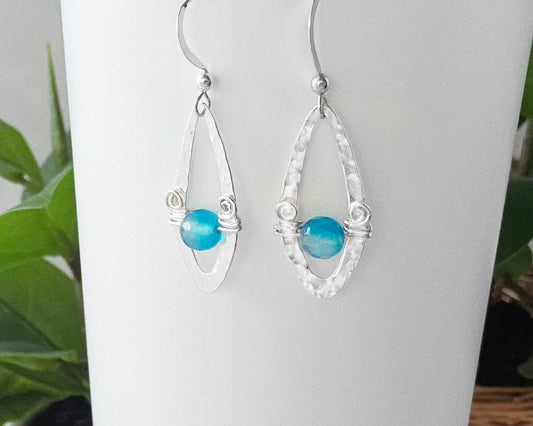 Long Sterling Silver Earrings with Blue Banded Agate stones and Celtic Eternity Coil designs on a wing like hammered design on French style earring hooks, on white background 