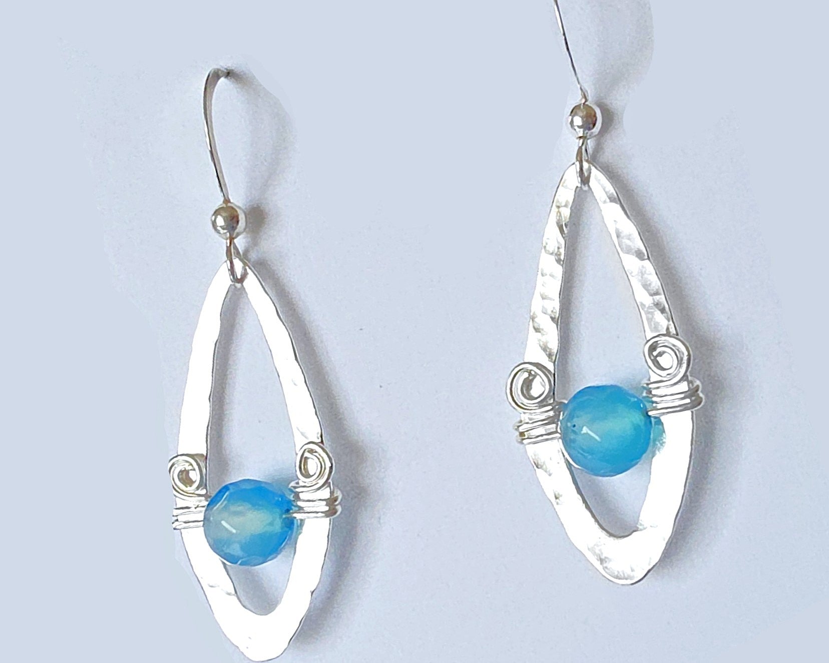 Long Sterling Silver Earrings with Blue Banded Agate stones and Celtic Eternity Coil designs on a wing like hammered design on French style earring hooks, on white background 