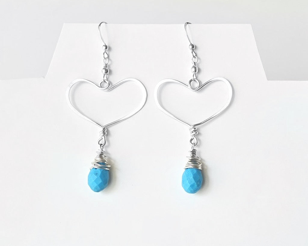 Long Sterling Silver Heart Dangle Earrings with large Hoop like Hearts and dangling Howlite drop shape stone, dangling from French style earring hooks, displayed on white background.