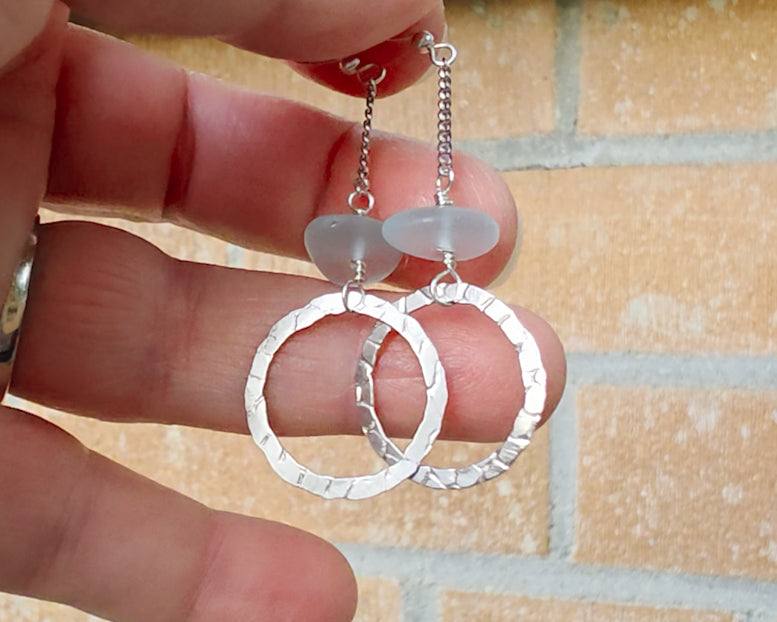 Long hoop dangle earrings on chain with aqua blue sea glass, with French hooks, displayed on hand with brick background 