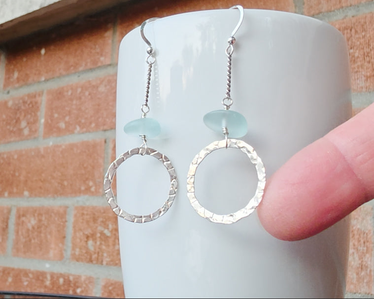 Long hoop dangle earrings on chain with aqua blue sea glass, with French hooks, displayed on white and brick and finger