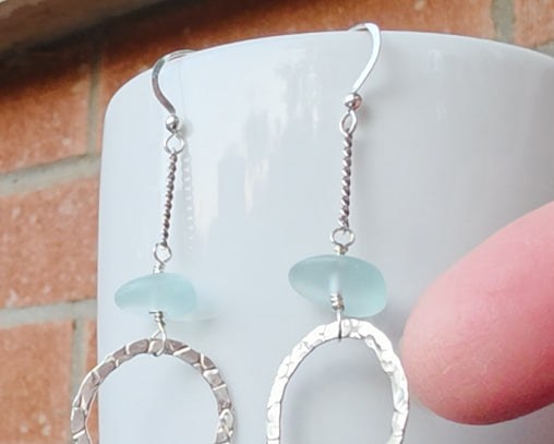Long hoop dangle earrings on chain with aqua blue sea glass, with French hooks, displayed on white and brick and finger