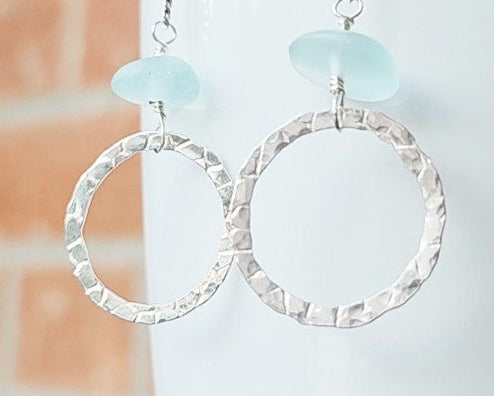 Long hoop dangle earrings on chain with aqua blue sea glass, with French hooks, displayed on white and brick. 