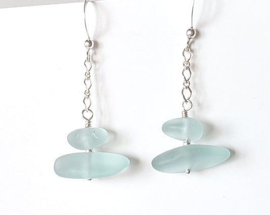 A pair of Long handmade Sterling Silver Pale Aqua blue Sea glass earrings with blue satin glass on long chain with french style earring hooks on white background