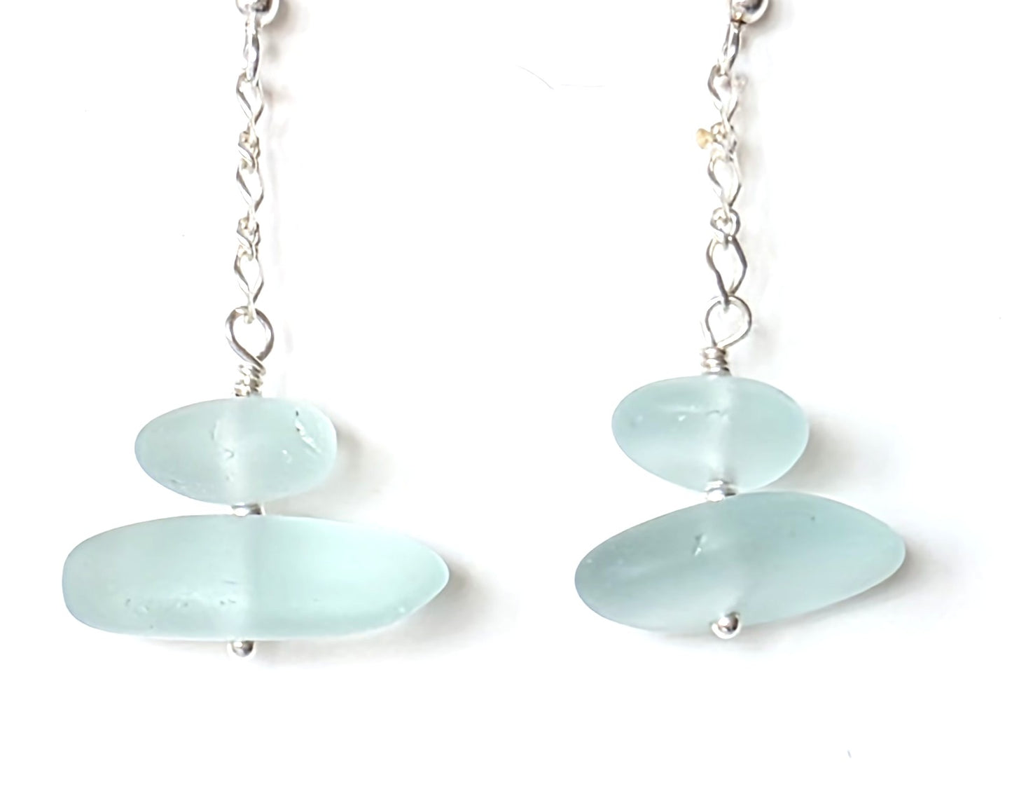 A pair of Long handmade Sterling Silver Pale Aqua blue Sea glass earrings with blue satin glass on long chain  on white background 