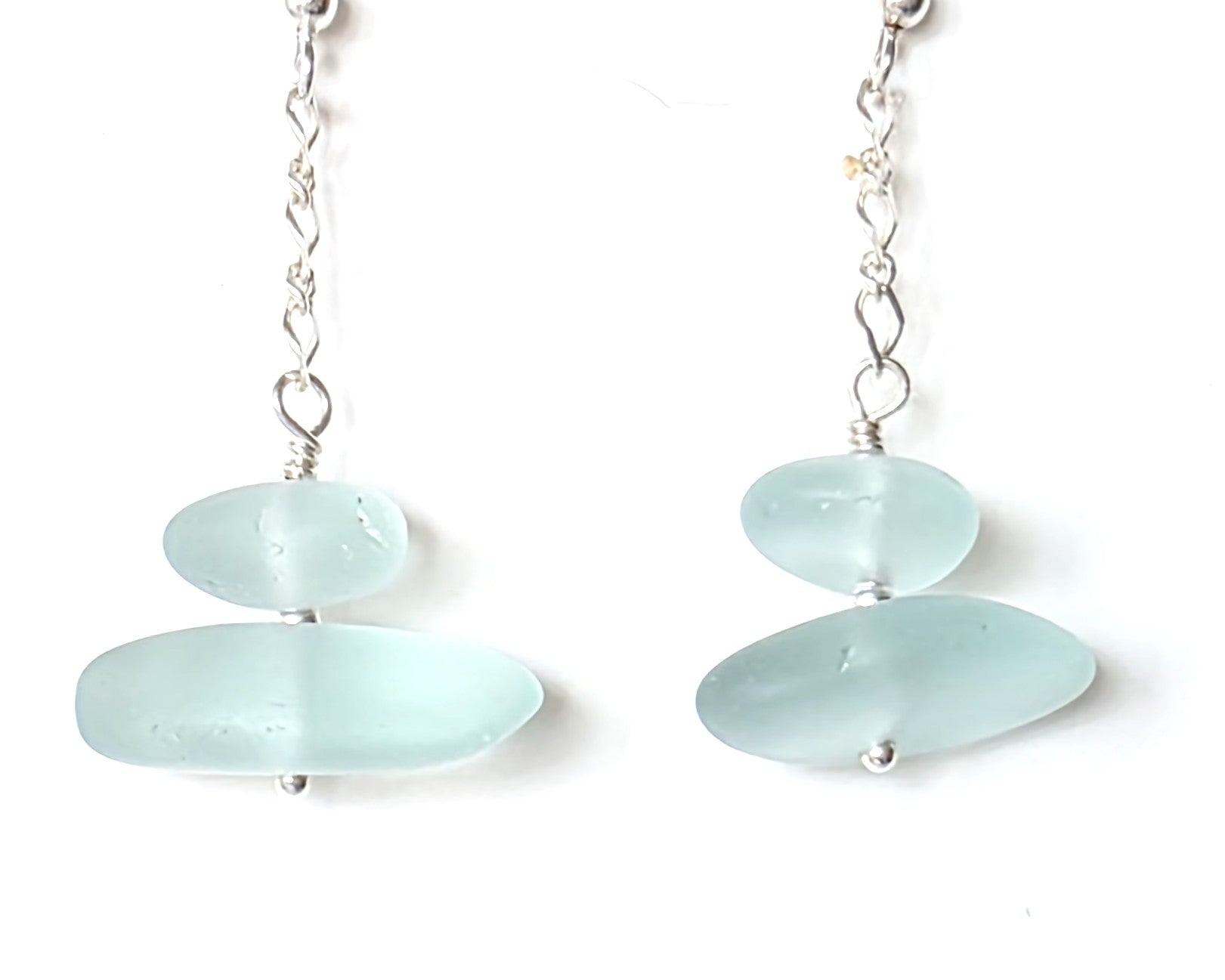 A pair of Long handmade Sterling Silver Pale Aqua blue Sea glass earrings with blue satin glass on long chain  on white background 