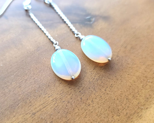 Long Sterling Silver Opaliate earrings with oval shaped stones dangling from long chains on wood background 