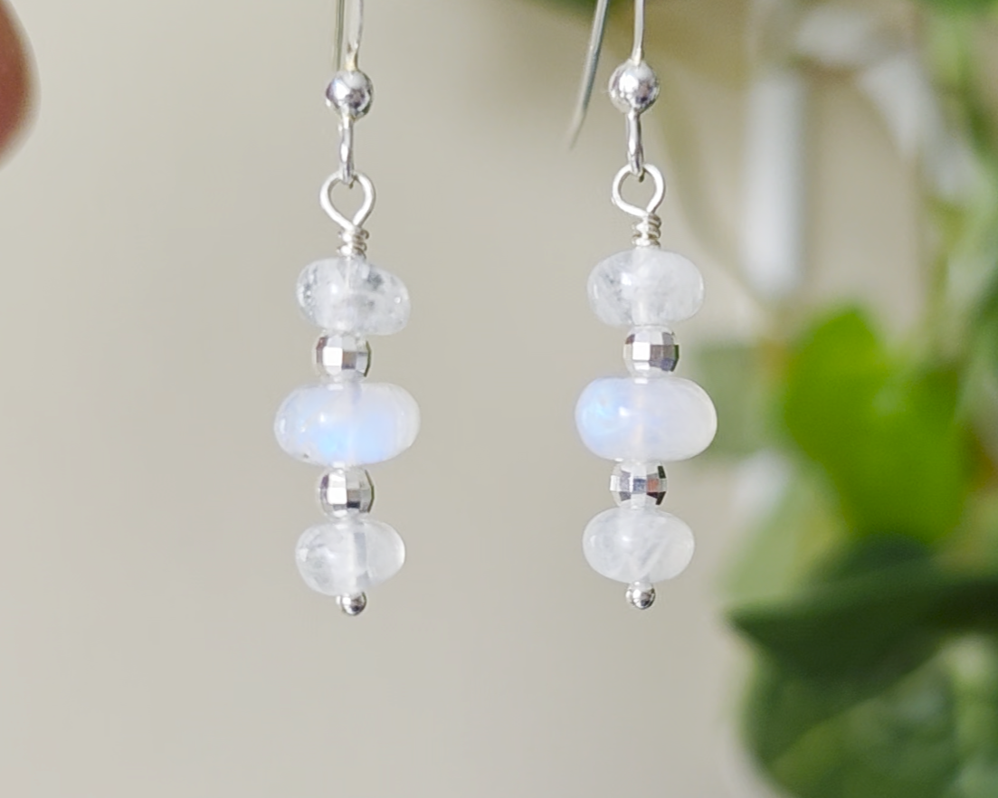 Sterling Silver Dangle Earrings with Three milky white Moonstones with blue and Sterling Silver sparkly beads dangling from silver French earring hooks with leaves in background 