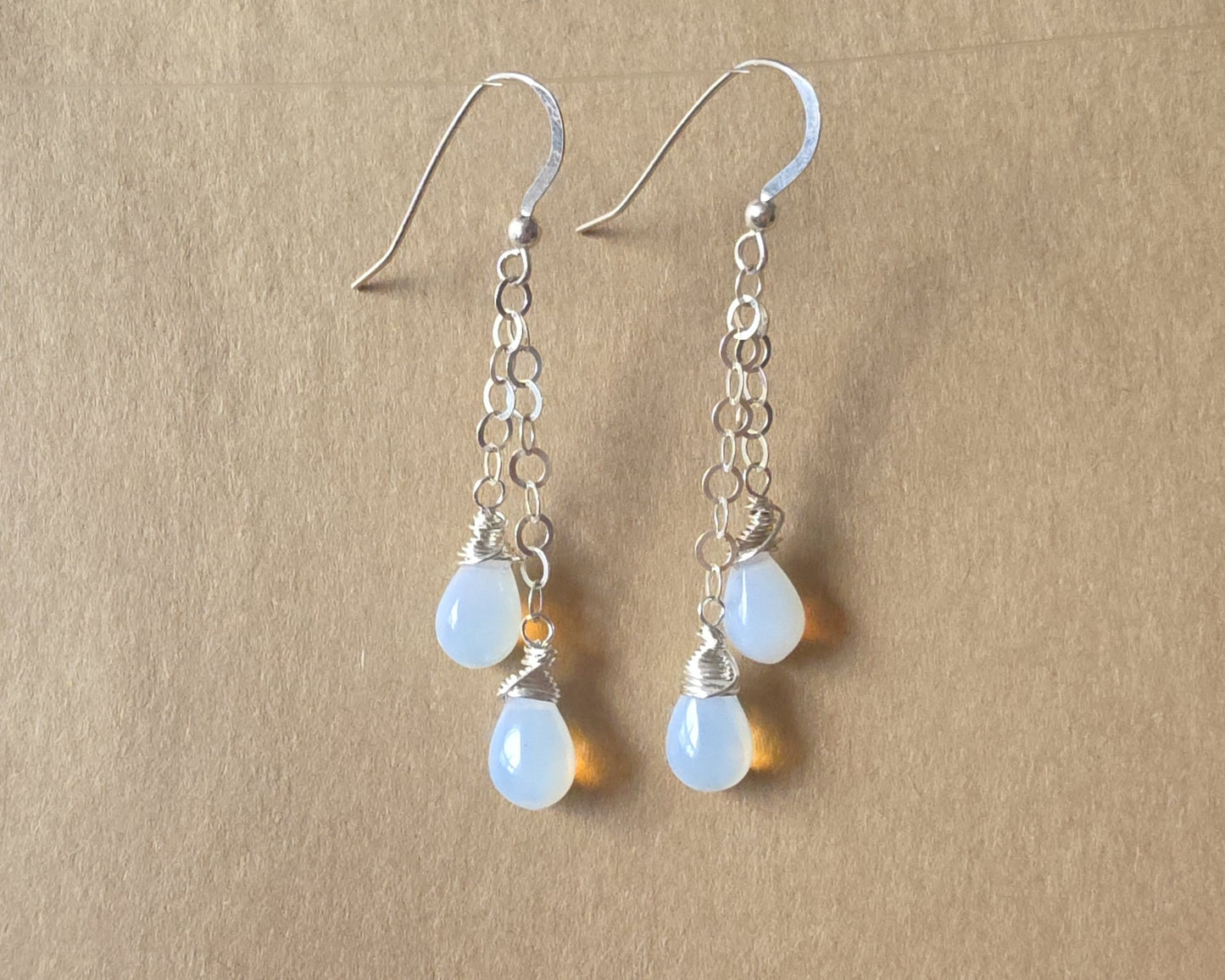 Long Sterling Silver double chain earrings with Opalite drops wrapped with Sterling Silver wire with French earring hooks on beige background 