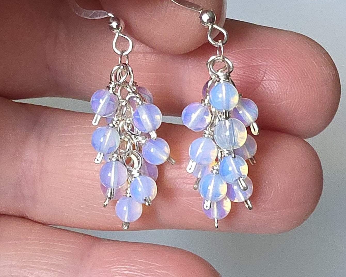 Sterling Silver Opalite Cluster earrings with blue gold stones on earring hooks, displayed in hand