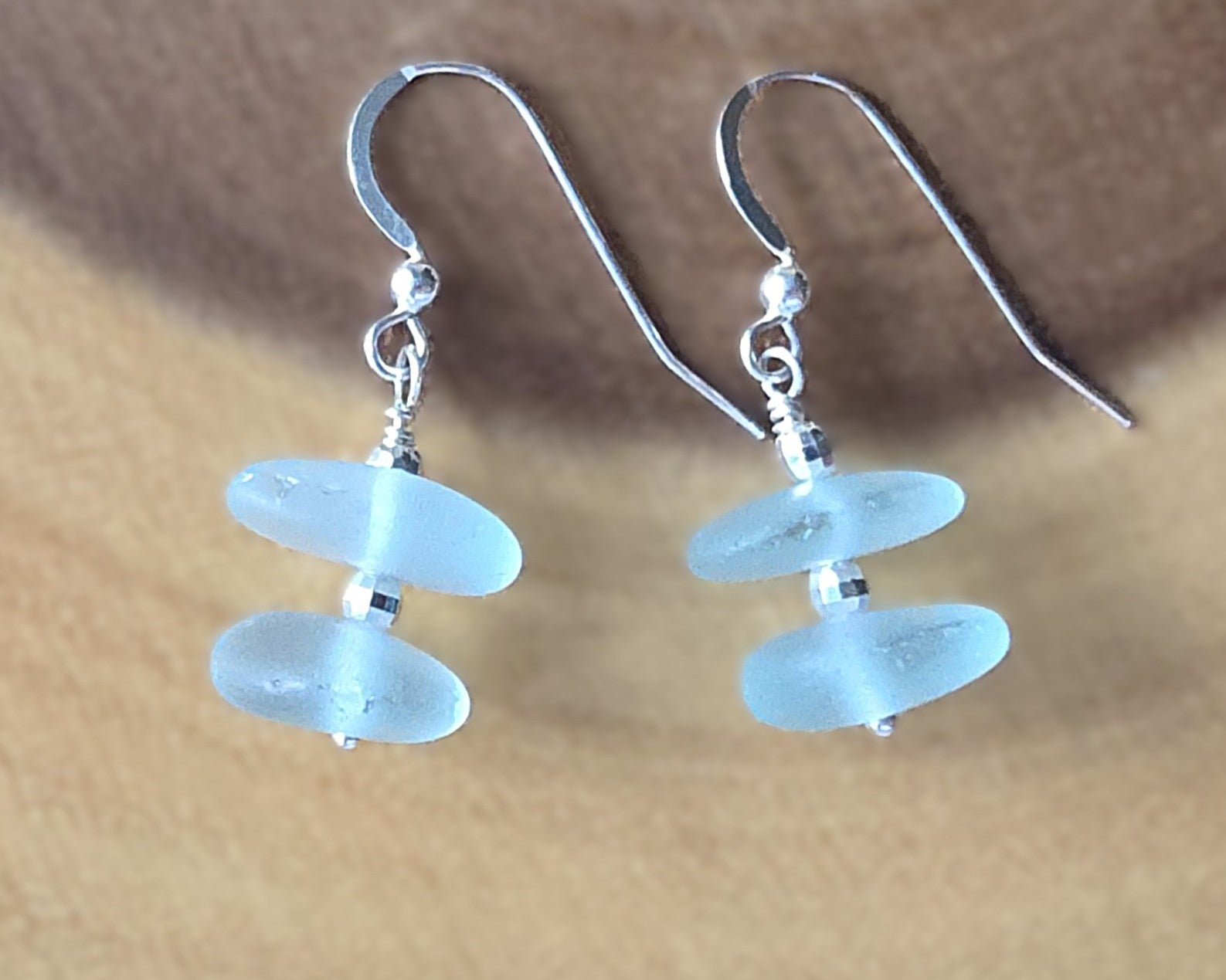 Pale Aqua blue Sea glass earrings with sparkly sterling silver beads on french style earring hooks on wood background 
