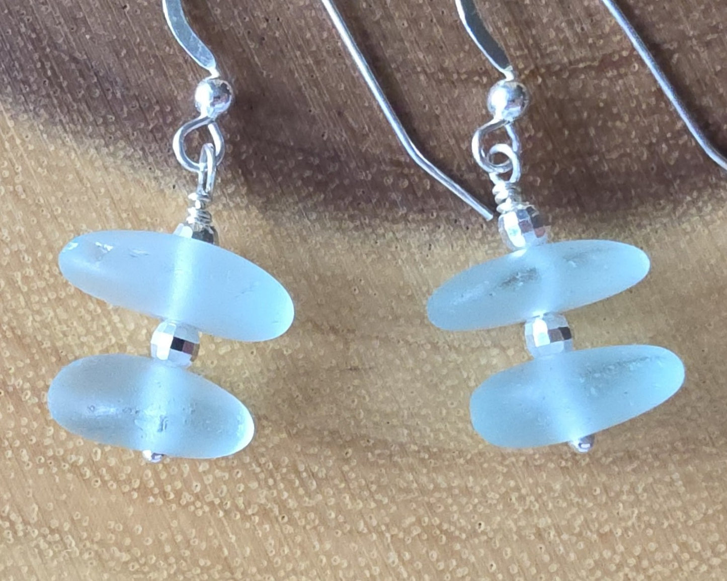 Pale Aqua blue Sea glass earrings with sparkly sterling silver beads on french style earring hooks on wood background 