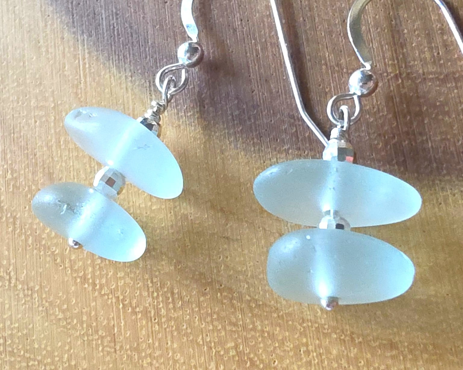 Pale Aqua blue Sea glass earrings with sparkly sterling silver beads on french style earring hooks on wood background 
