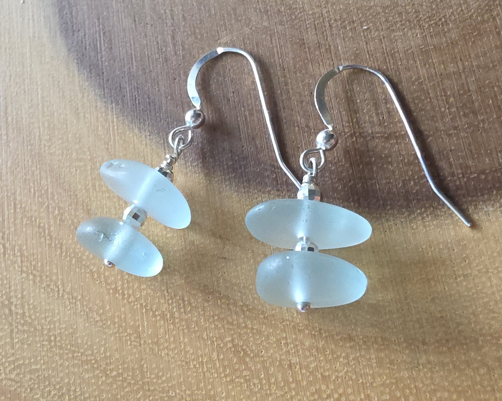 Pale Aqua blue Sea glass earrings with sparkly sterling silver beads on french style earring hooks on wood background 
