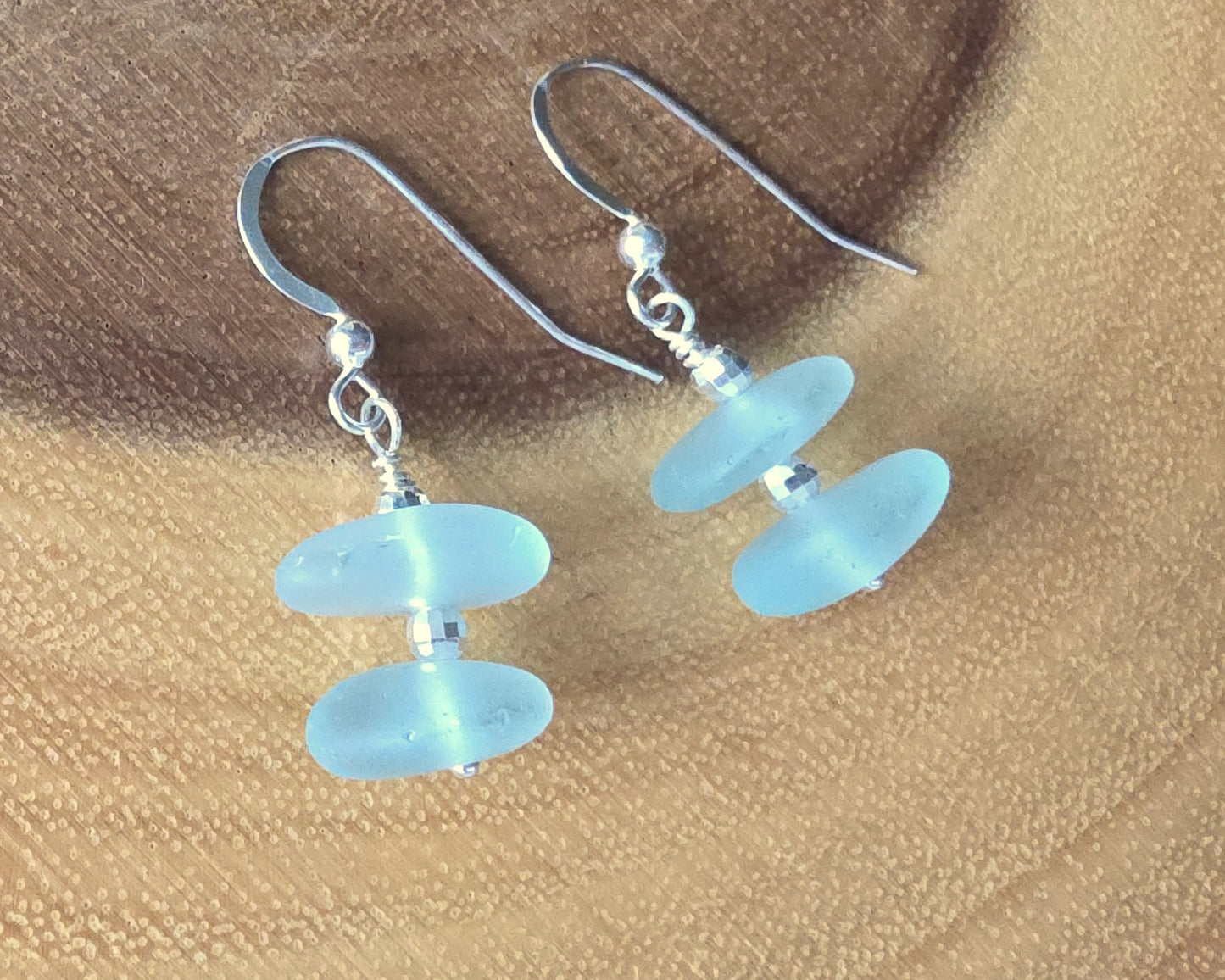 Pale Aqua blue Sea glass earrings with sparkly sterling silver beads on french style earring hooks on wood background 