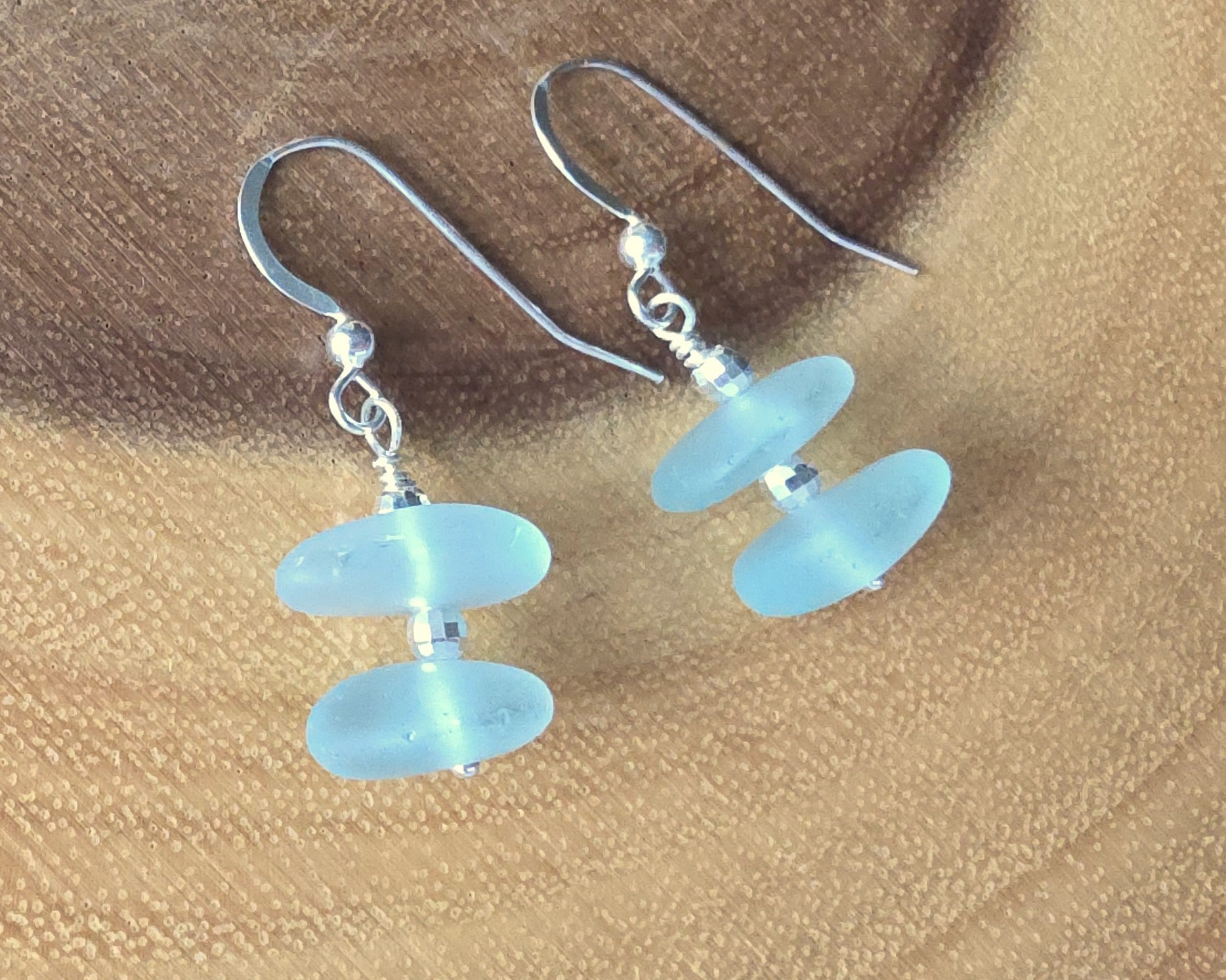 Pale Aqua blue Sea glass earrings with sparkly sterling silver beads on french style earring hooks on wood background 