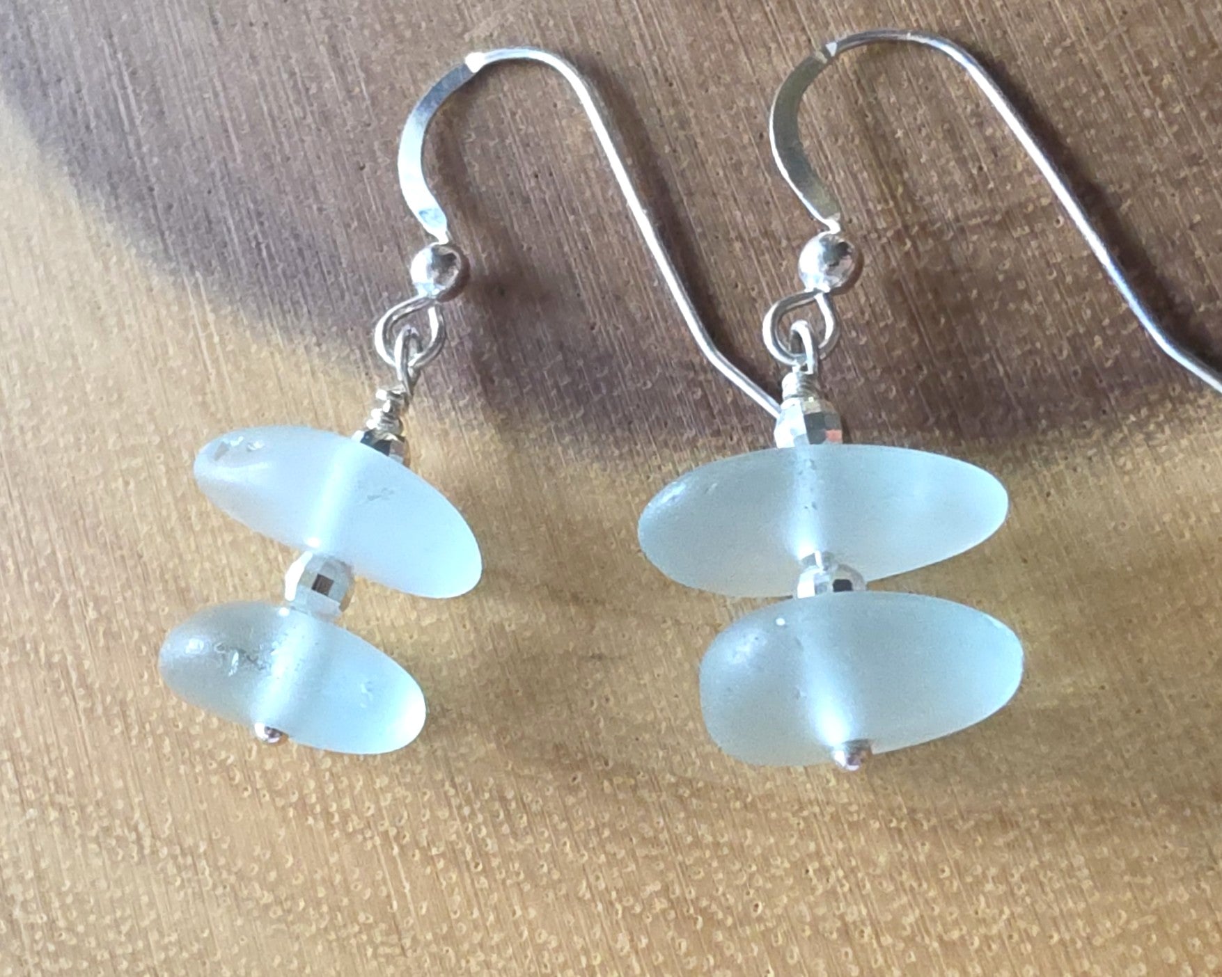 Pale Aqua blue Sea glass earrings with sparkly sterling silver beads on french style earring hooks on wood background 