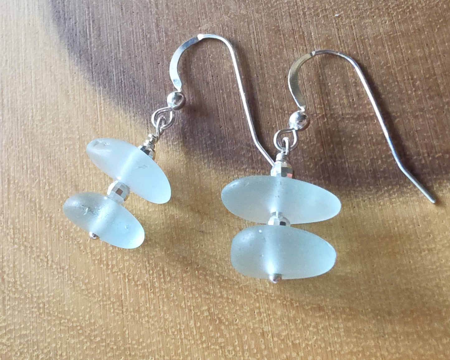 Pale Aqua blue Sea glass earrings with sparkly sterling silver beads on french style earring hooks on wood background 