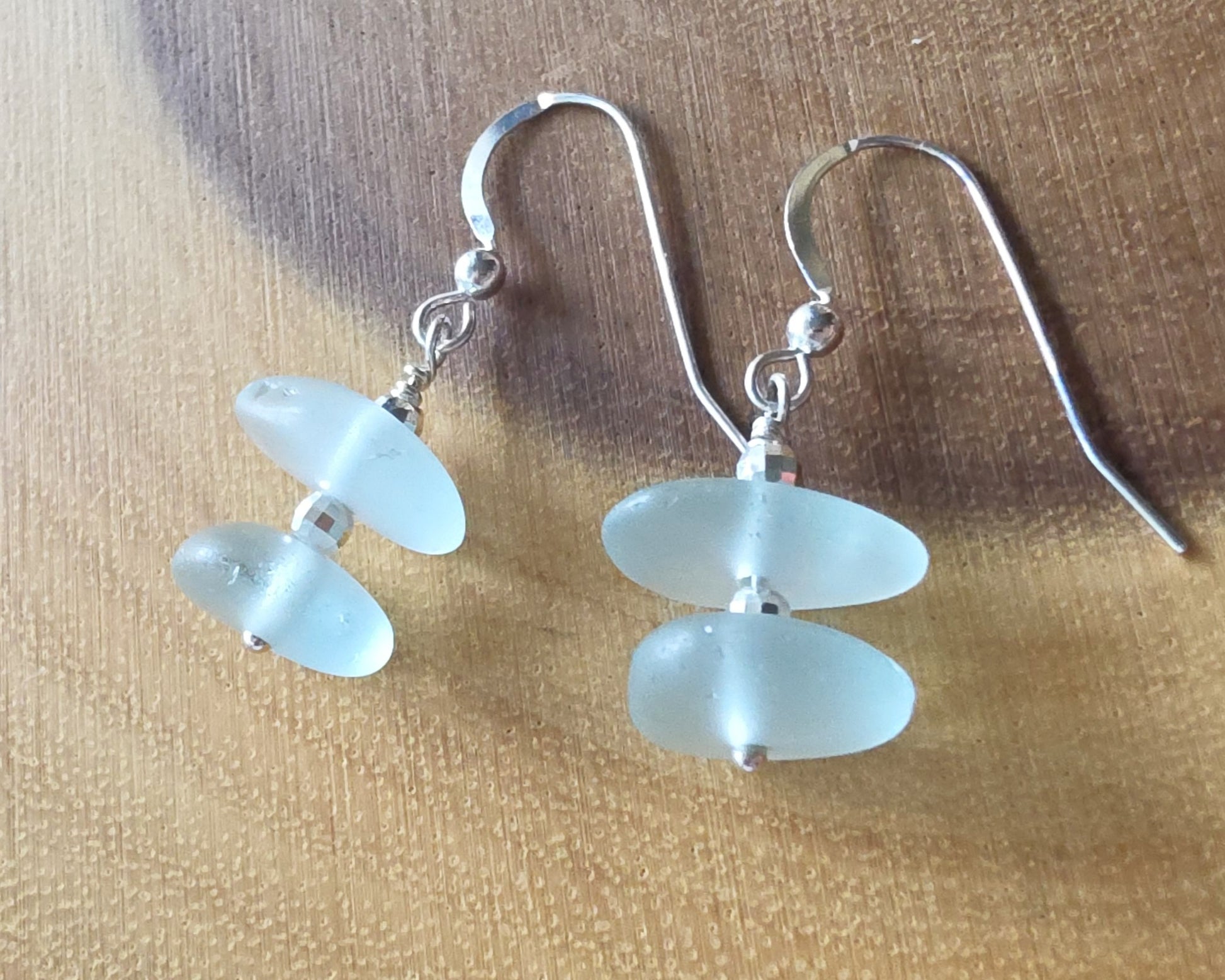 Pale Aqua blue Sea glass earrings with sparkly sterling silver beads on french style earring hooks on wood background 
