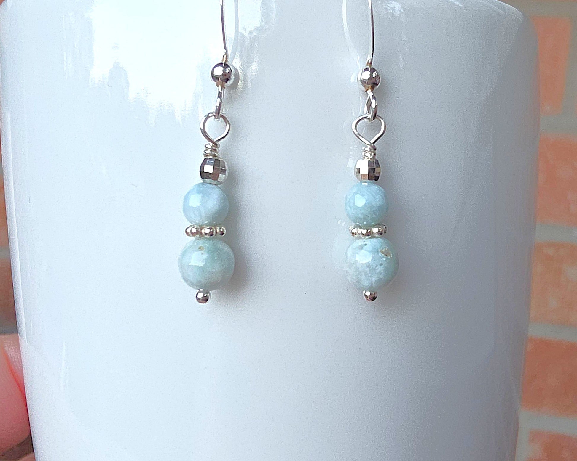 A pair of pale blue gemstone sterling silver dangle earrings on french earring hooks on white 