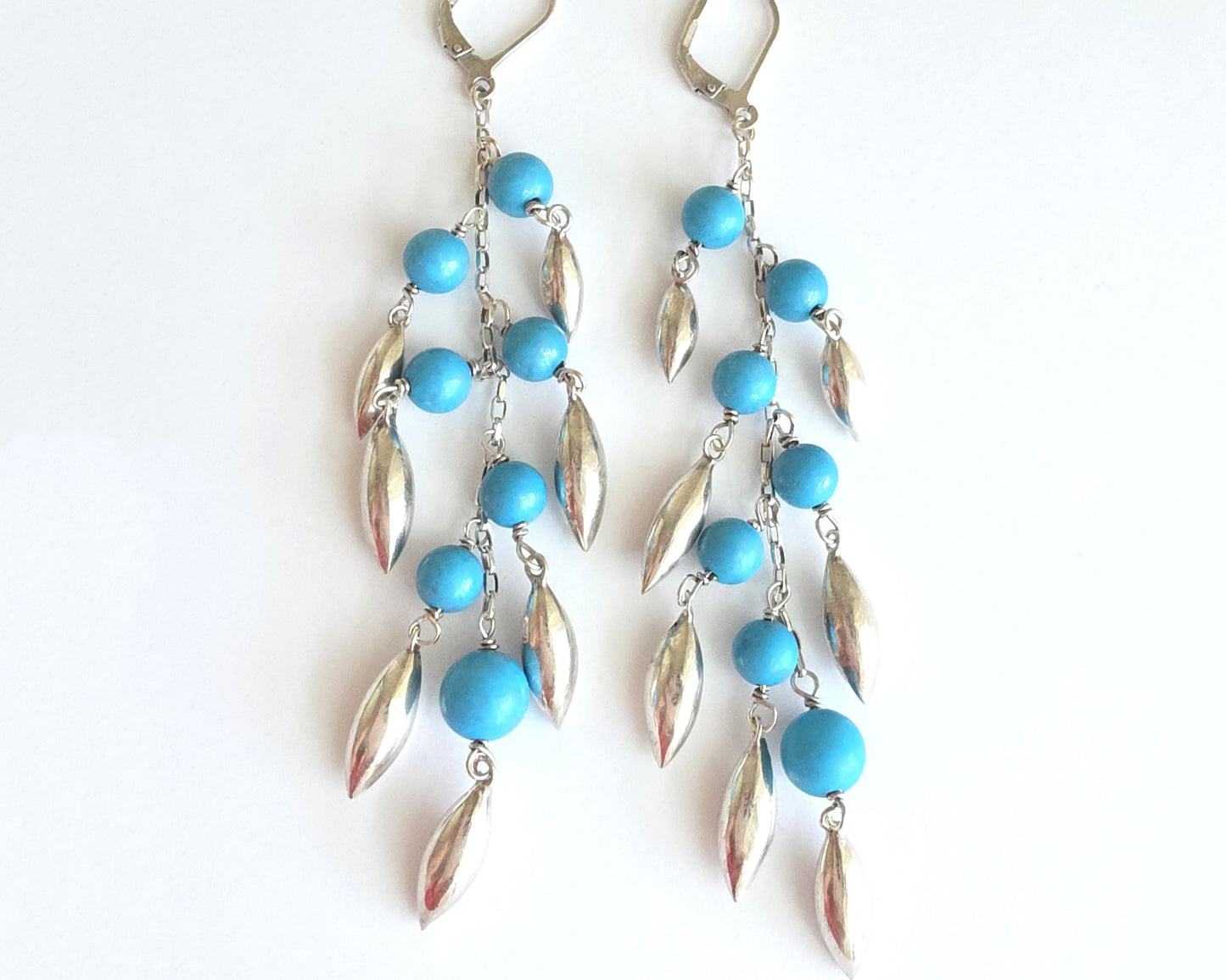 Long Turquoise Blue beaded Dangle Earrings with Pod /leaf shape silver pendants and lever back earrings hooks on white background 