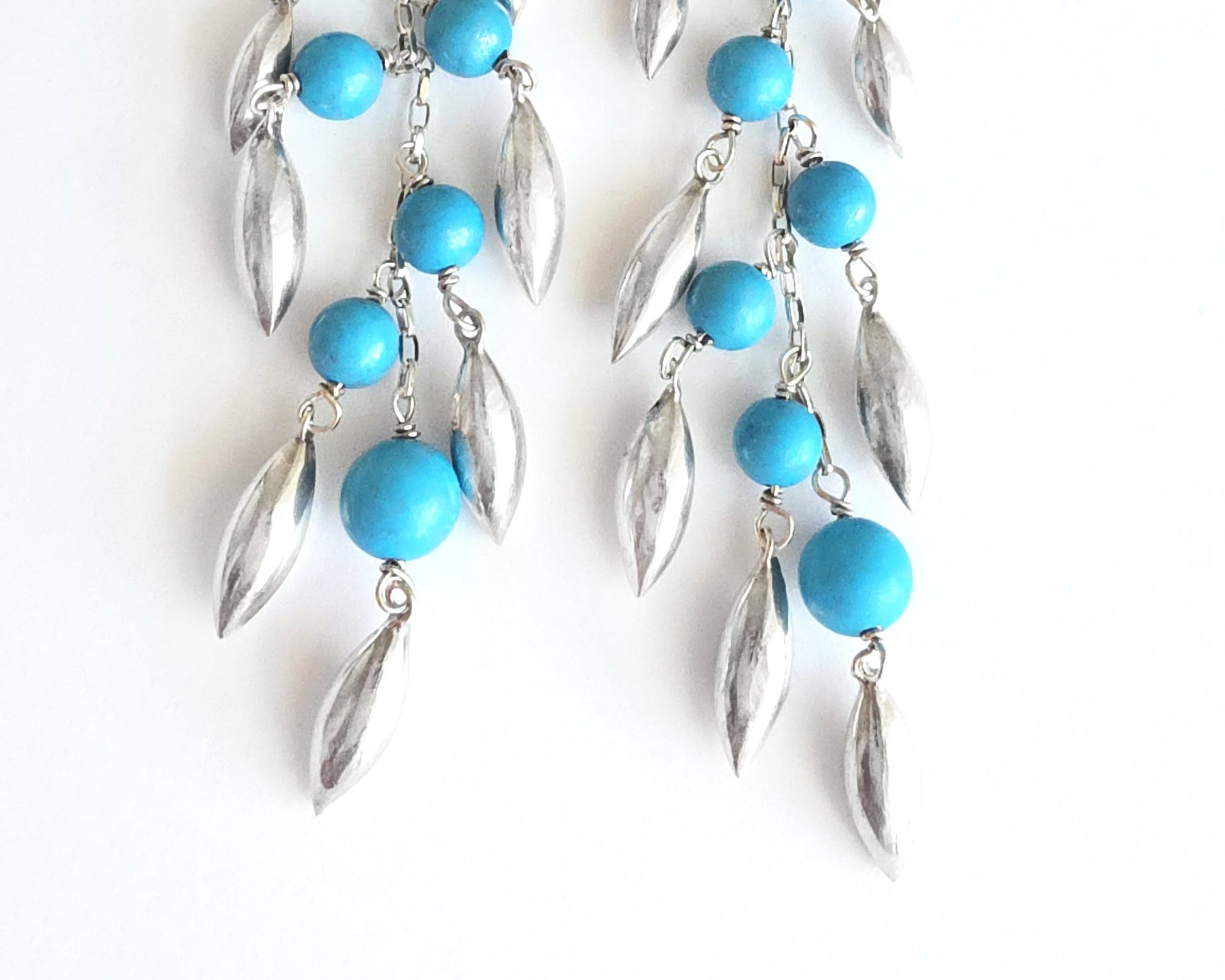 Long Turquoise Blue beaded Dangle Earrings with Pod /leaf shape silver pendants on white background 