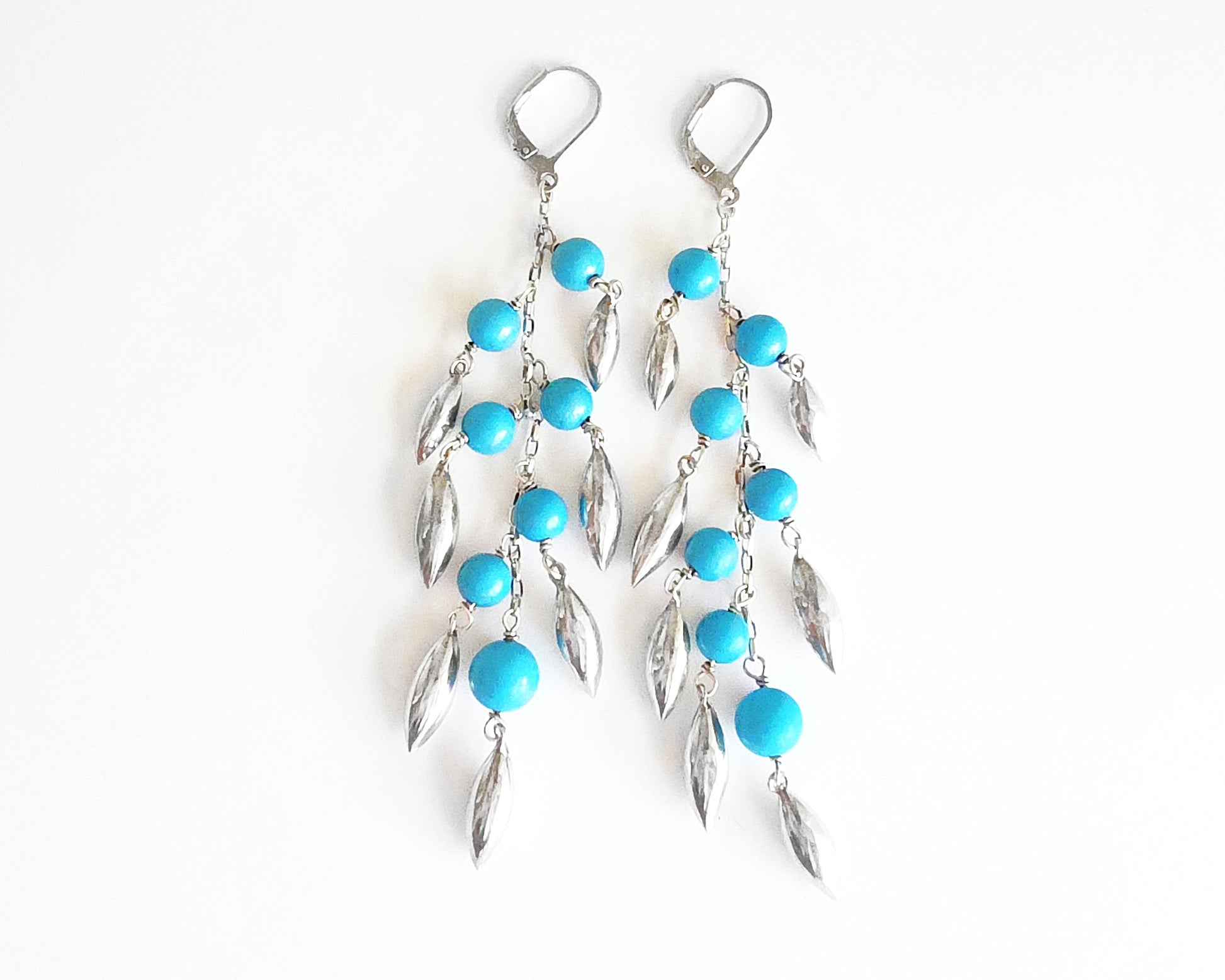 Long Turquoise Blue beaded Dangle Earrings with Pod /leaf shape silver pendants and lever back earrings hooks on white background 