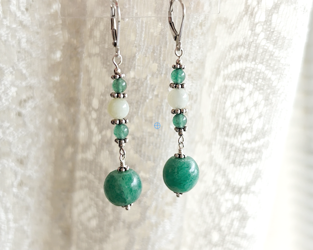 Long green gemstone earrings with deeper green aventurine and pale green jade with decorative sterling silver beads on lever back earring hooks with lace background