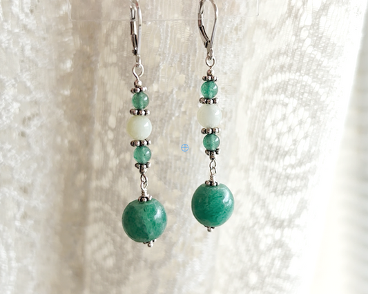 Long green gemstone earrings with deeper green aventurine and pale green jade with decorative sterling silver beads on lever back earring hooks with lace background