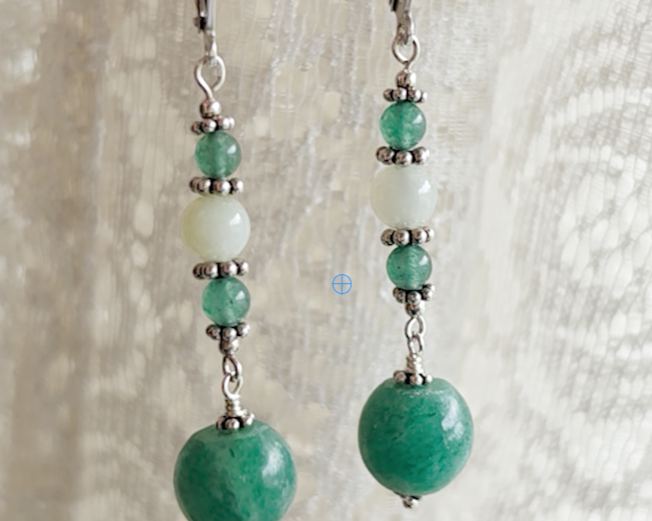 Long green gemstone earrings with deeper green aventurine and pale green jade with decorative sterling silver beads with lace background