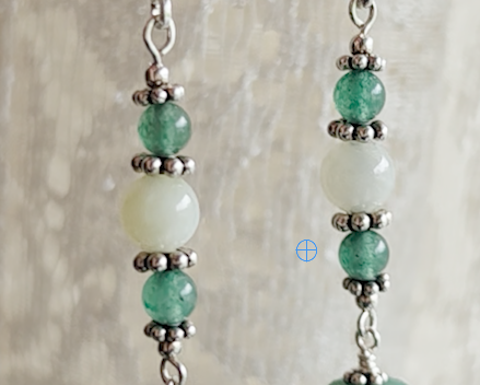 Long green gemstone earrings with deeper green aventurine and pale green jade with decorative sterling silver beads with lace background
