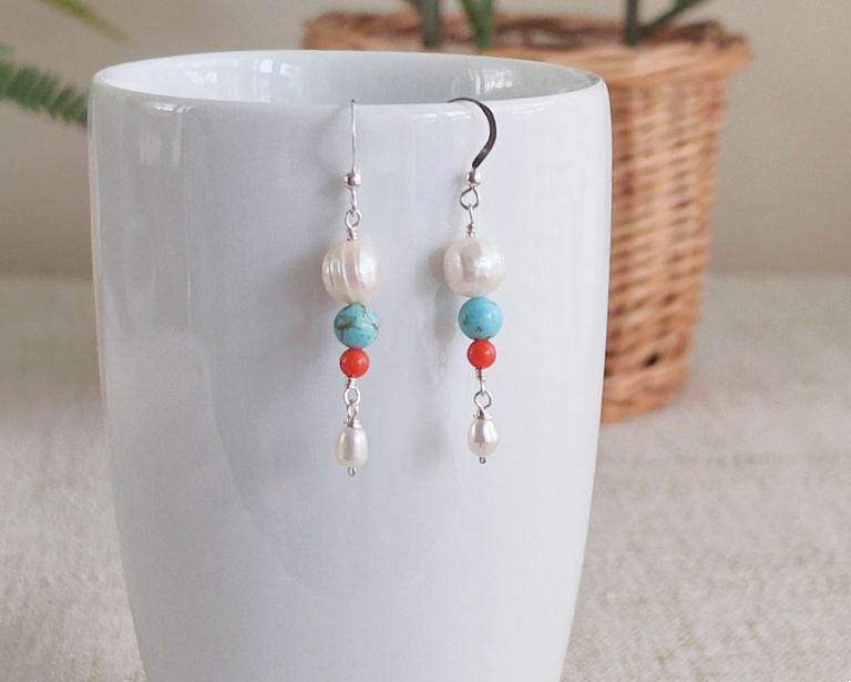 Long Turquoise Coral and Freshwater Cultured pearl dangle beaded earrings on silver french hooks on white vase