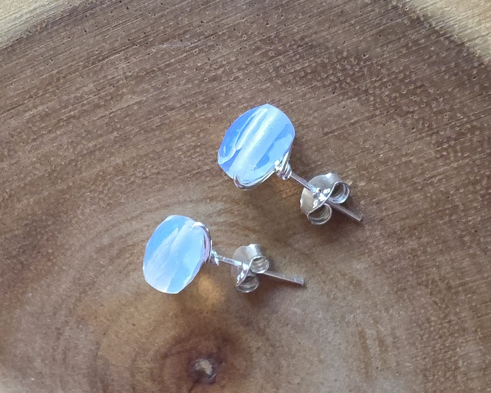 Opalite Stud earrings with milky white blue and gold hue sparkly stones on silver, displayed on wood