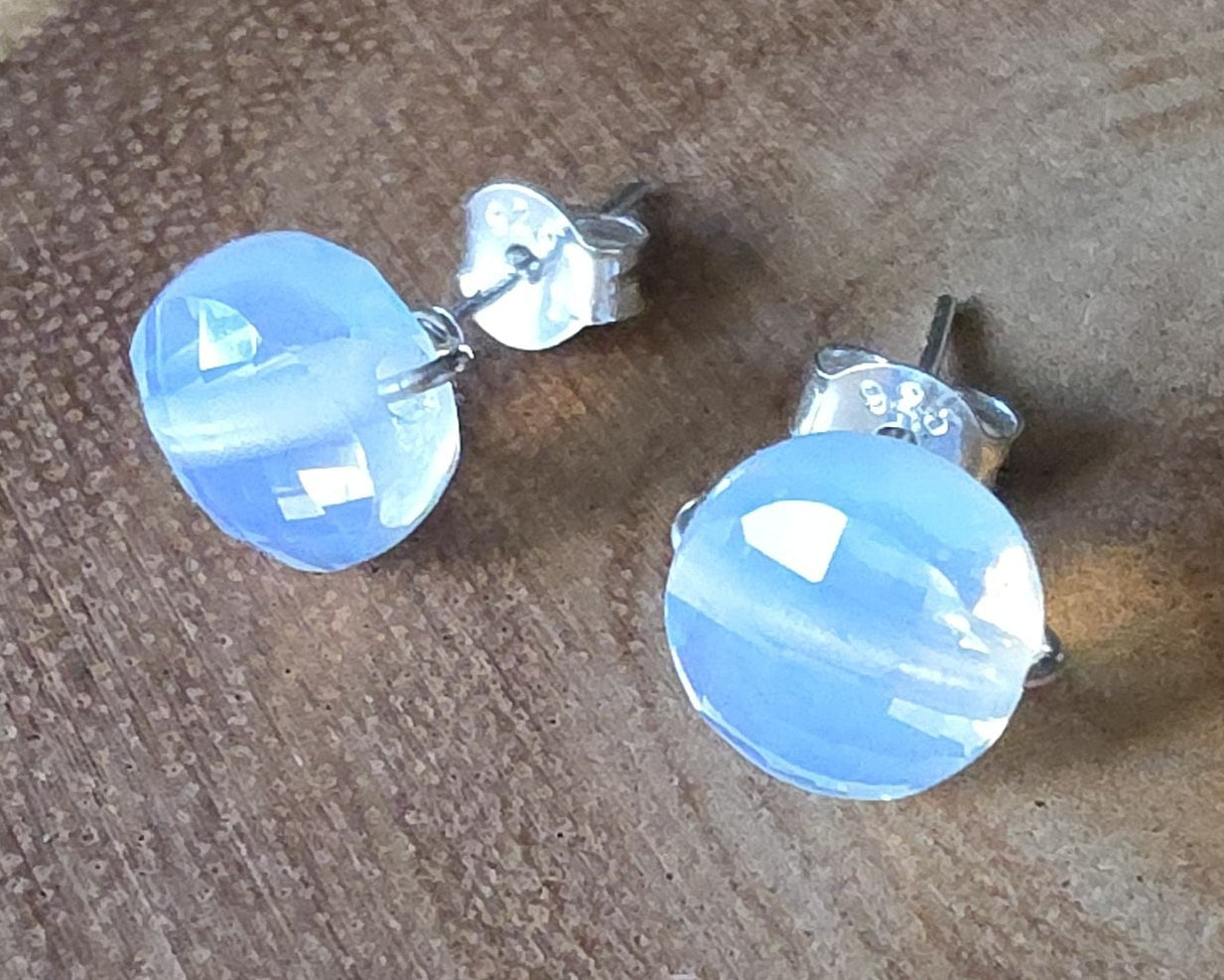 Opalite Stud earrings with milky white blue and gold hue sparkly stones on silver, displayed on wood