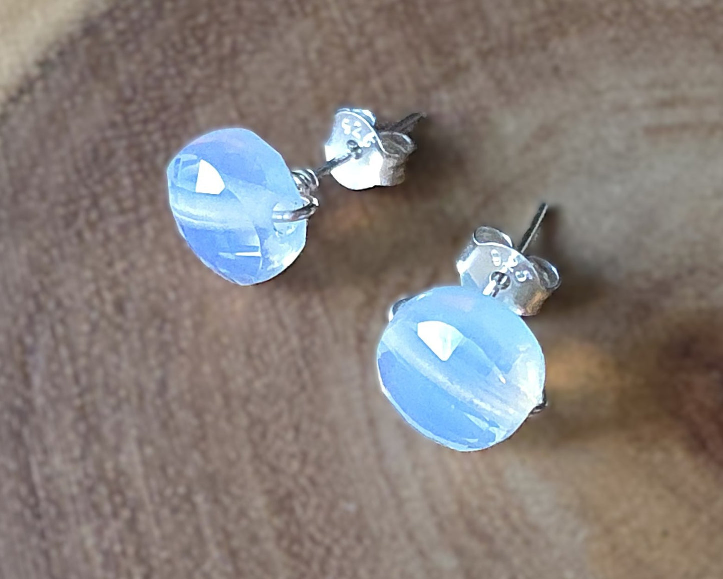 Opalite Stud earrings with milky white blue and gold hue sparkly stones on silver, displayed on wood