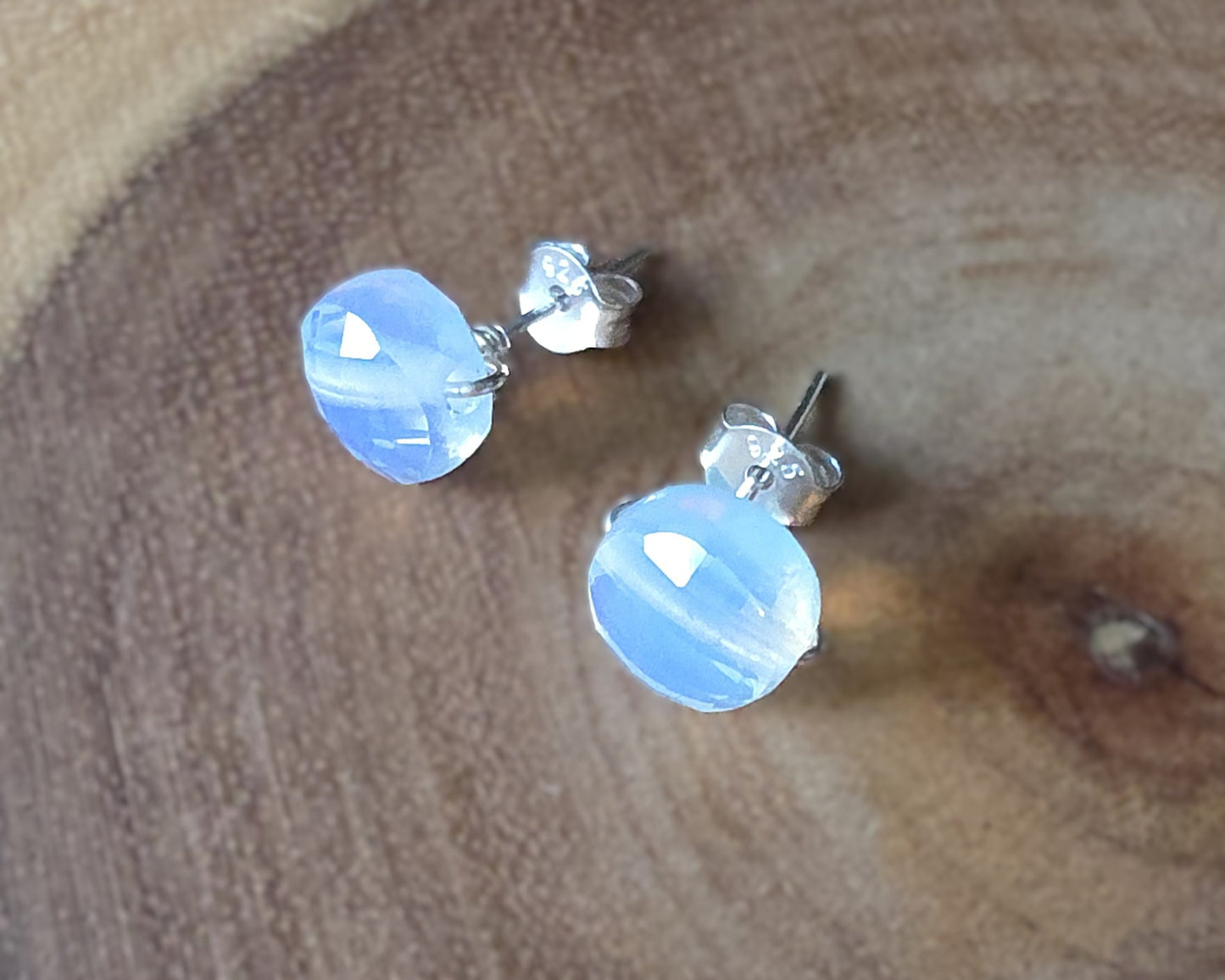 Opalite Stud earrings with milky white blue and gold hue sparkly stones on silver, displayed on wood
