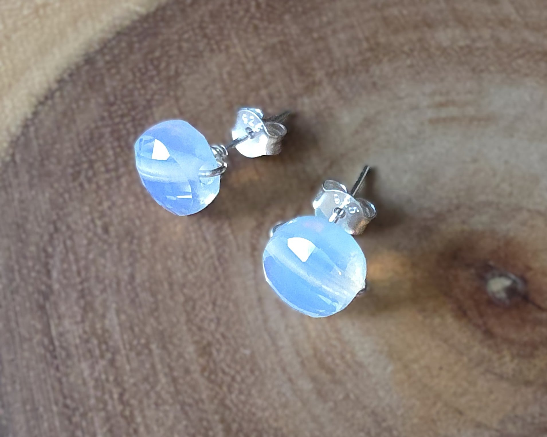 Opalite Stud earrings with milky white blue and gold hue sparkly stones on silver, displayed on wood