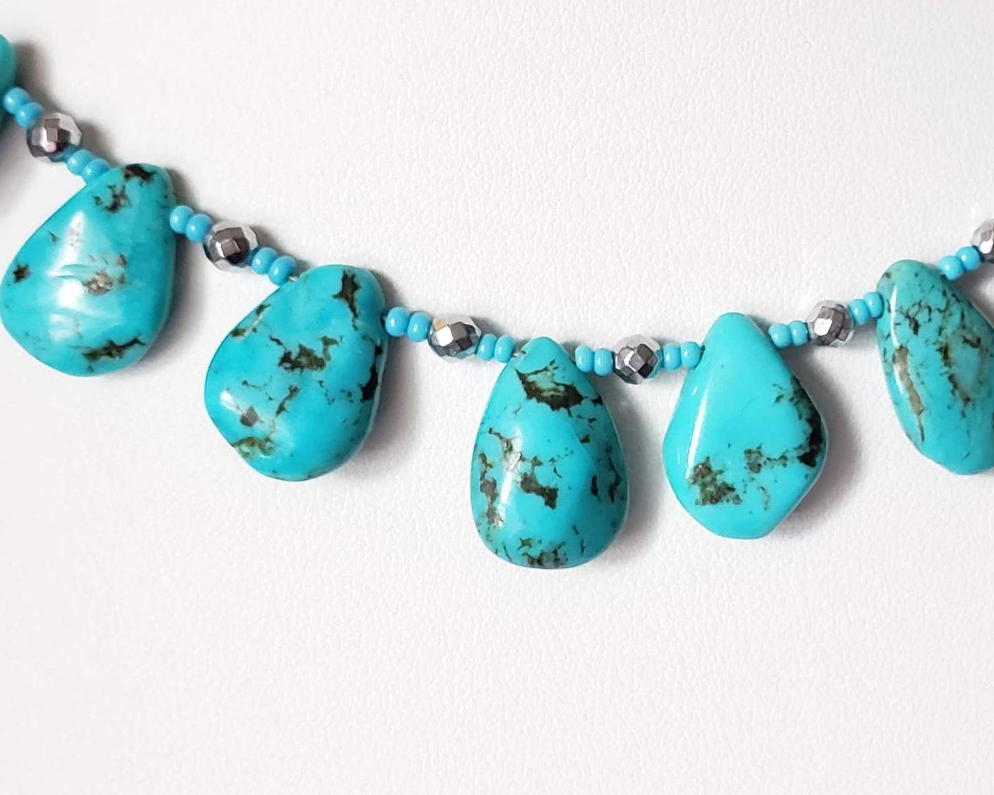 Turquoise Beaded Collar Necklace with blue Turquoise Drop Shaped Stones, sparkly silver Hematite beads and tiny glass seed beads, on white display and background 
