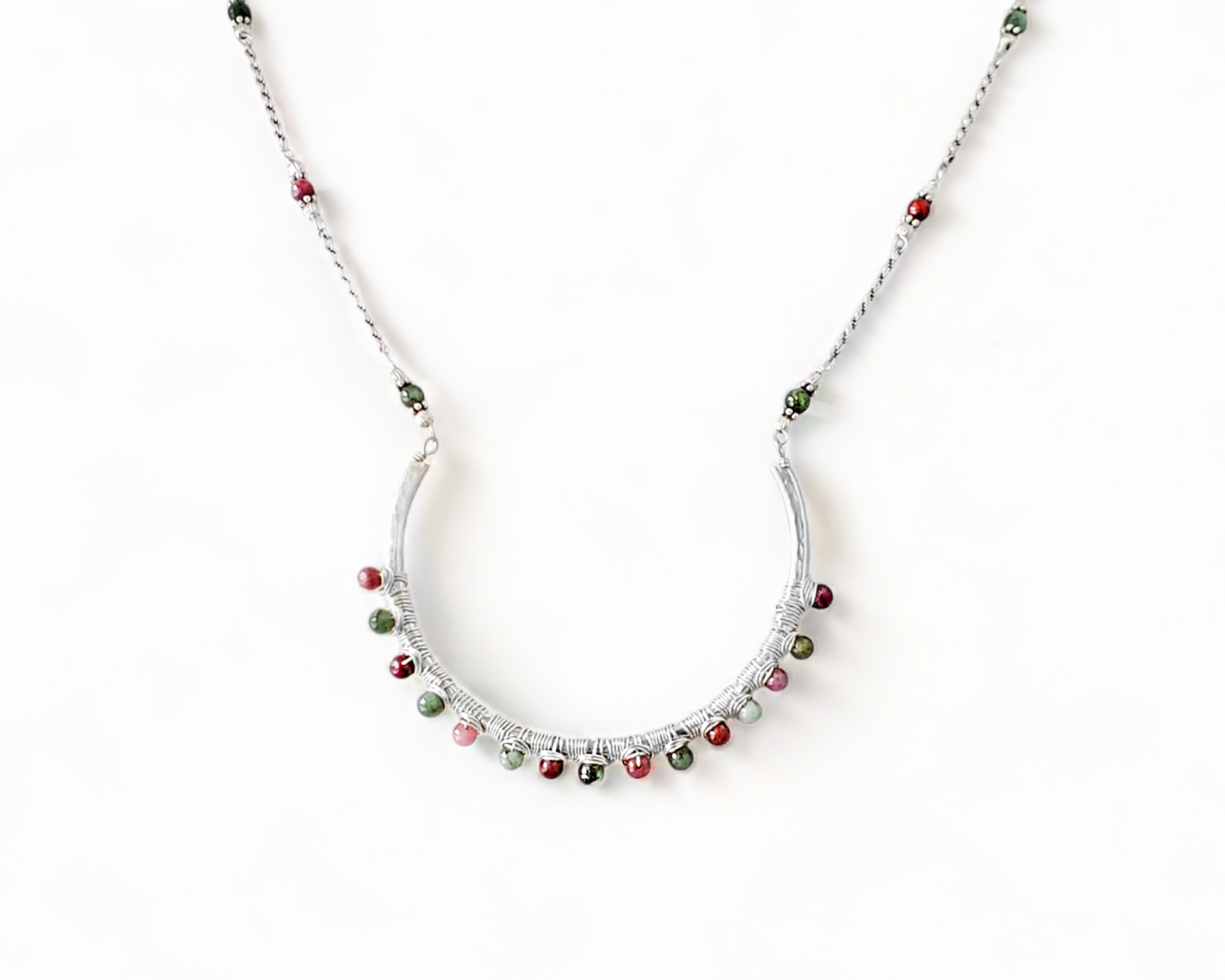 Sterling Silver Necklace with Rubies and Emerald, a wire wrapped curved pendant on white background 