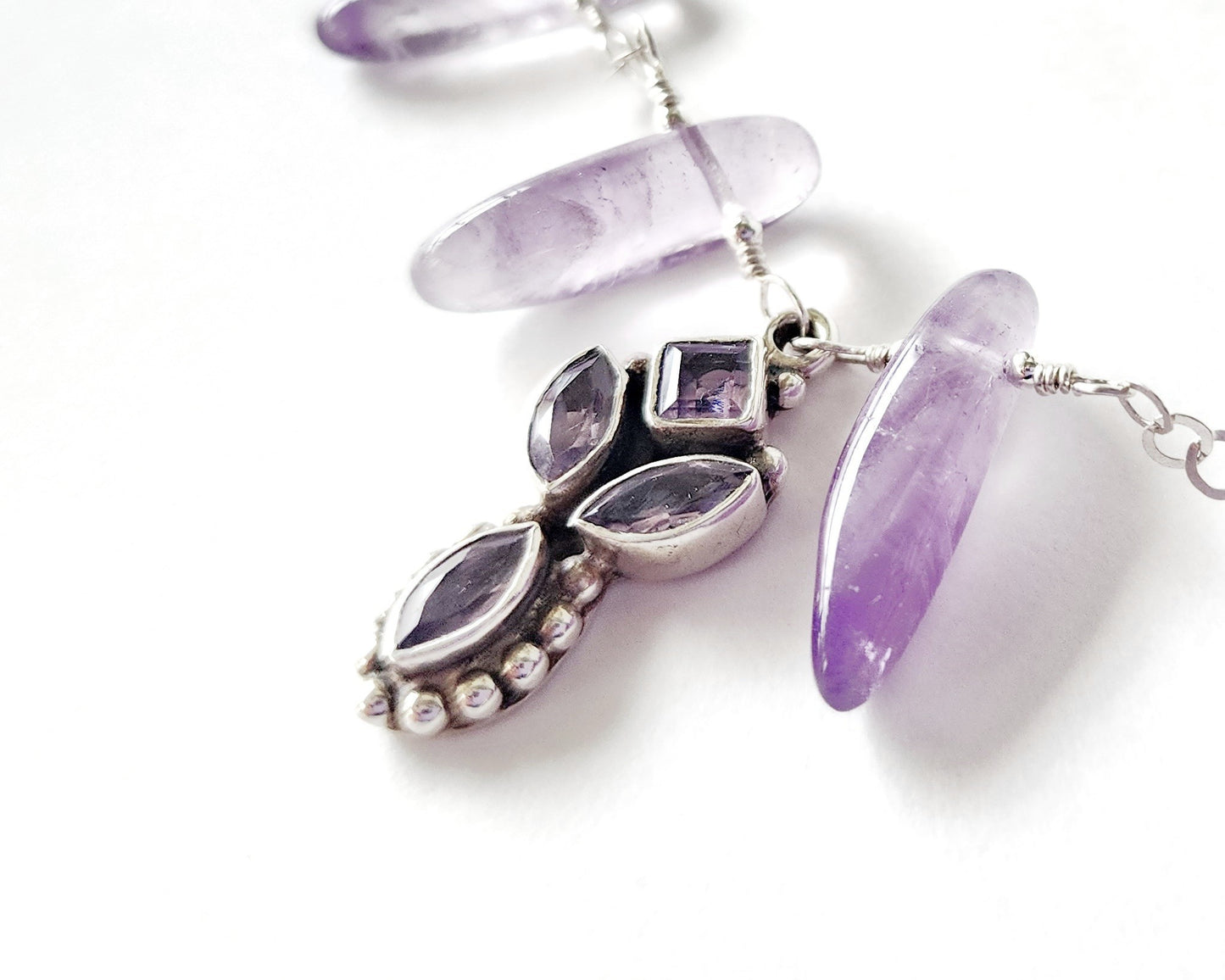 Amethyst Sterling Silver almost fan style Necklace with Decorative Silver pendant with sparkly faceted stones and wire wrapped long stones on white background 